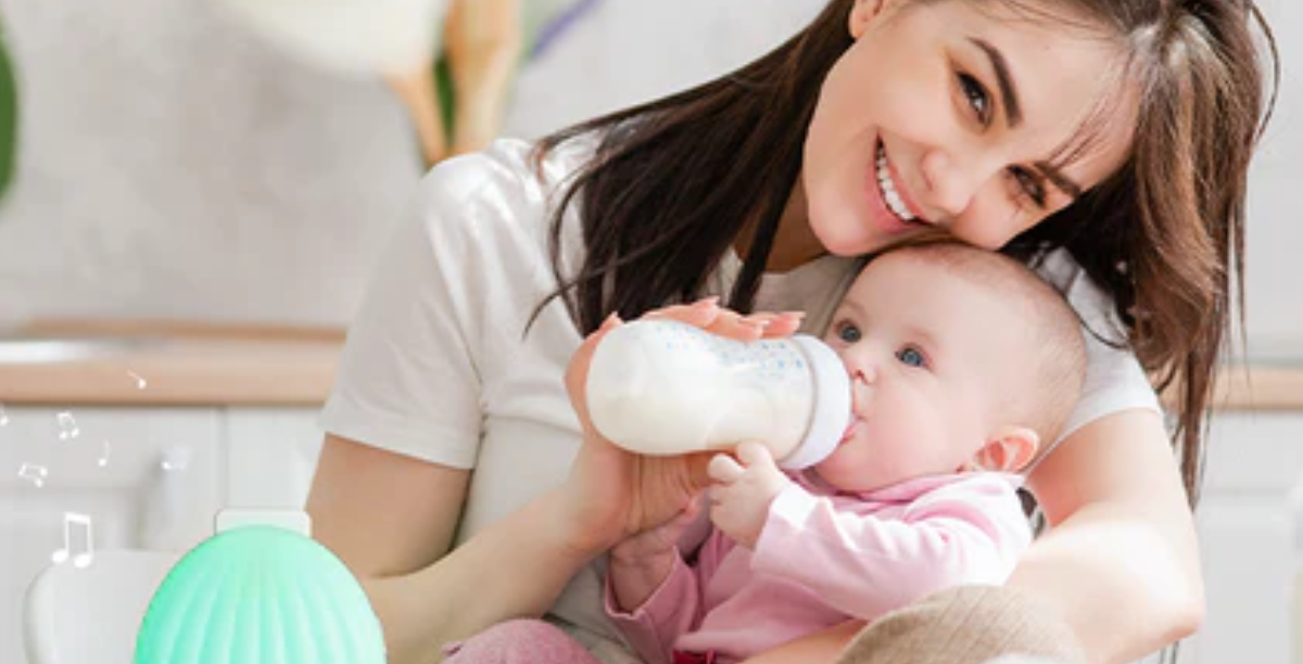 A woman smiles while feeding a baby with a bottle
