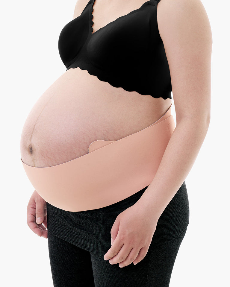 Translation missing: fr.Light beige Momcozy Maternova belly band shown on a pregnant model wearing a black bra and grey leggings