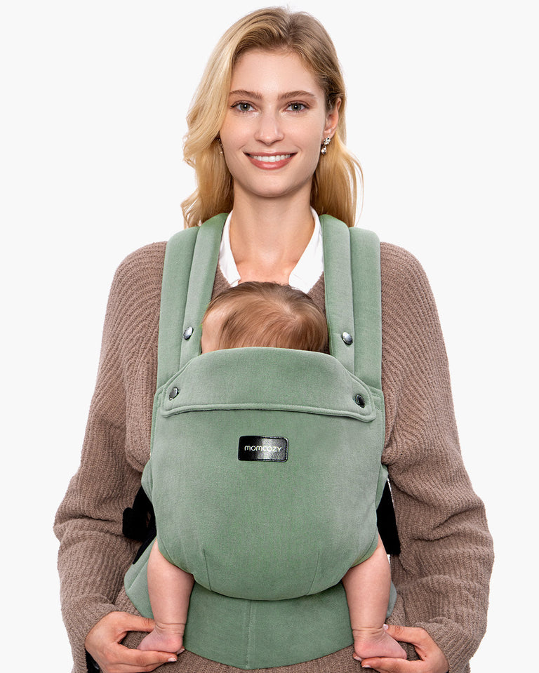 Translation missing: fr.Momcozy PureHug baby carrier in sage green, babywearing comfortably. Mother and baby are smiling