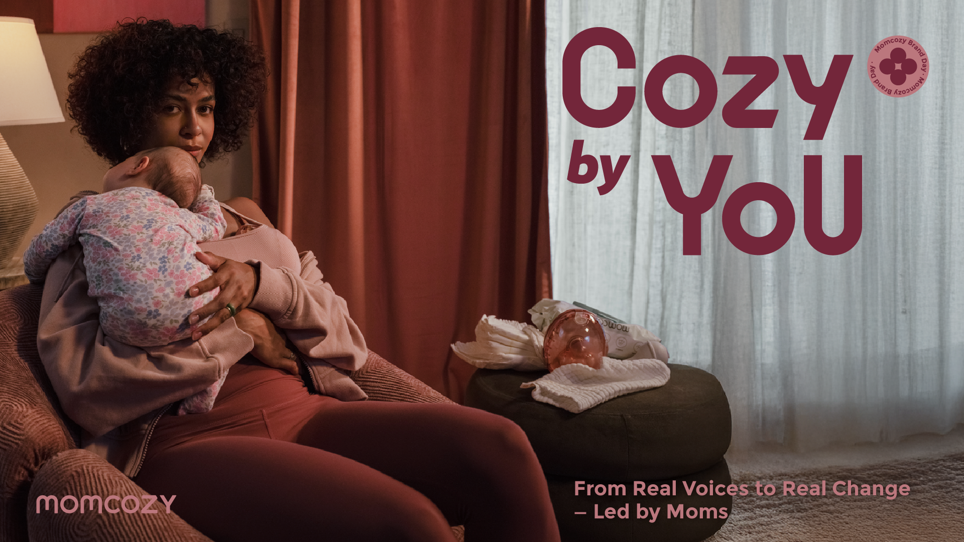 Woman holding a baby on a couch with 'Cozy by You' branding in the background.